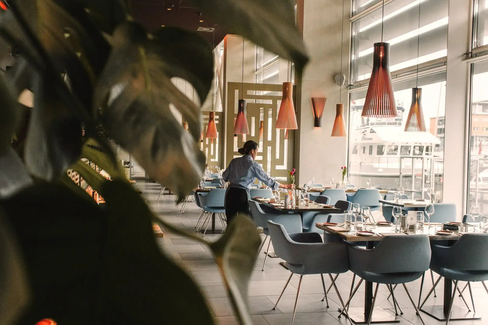 Medewerker zet tafels klaar in modern hotelrestaurant aan het water